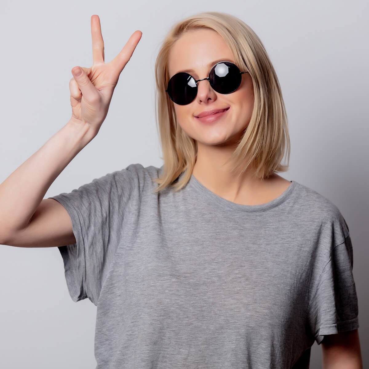 Smiling blonde woman in sunglasses on white background